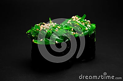Close-up of japanese gunkan sushi with chukka and sesame seeds wrapped in nori seaweed on dark background. Stock Photo
