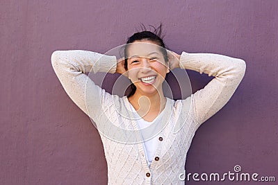 Close up joyful asian woman standing with hands behind head Stock Photo