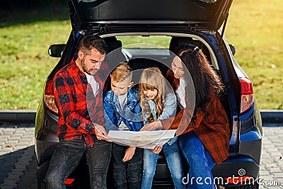 Close up of joyful pleasant family which gethering on their vacation with teen children and using road map to choose the Stock Photo