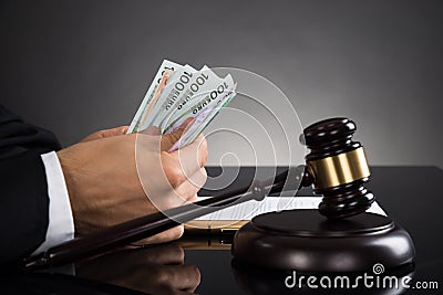 Close-up Of Judge Counting Banknote At Desk Stock Photo