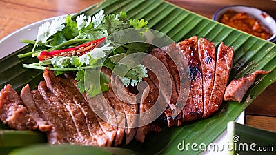 Close up juicy yummy fried sliced pork on green banana leaf , popular traditional Thai food Stock Photo