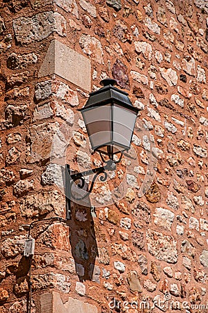 Close-up of lamp stuck in stone wall in sunny day, in Roussillon. Stock Photo