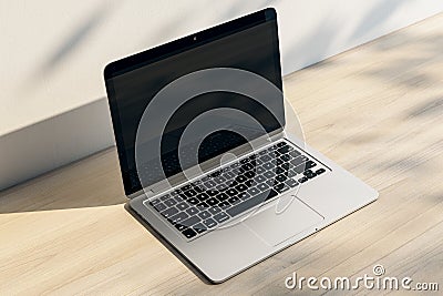 Close up of laptop with empty screen and reflections at wooden workplace with shadows. Editorial Stock Photo