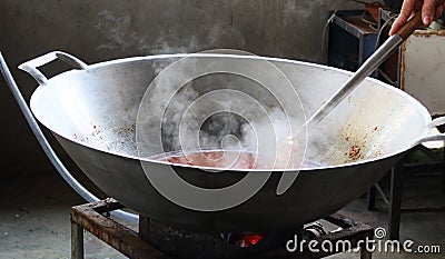 Close-up, large iron pan cooking, smoke and heat inside the kitchen. Stock Photo