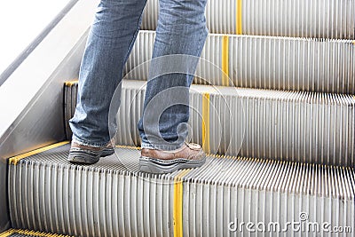 Close up leg of Men wear jeans, leather shoes. Standing on the escalator Stock Photo