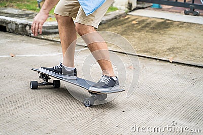 Close up a legs of active Asian hipster guy ride Surf Skate Board on street in front of his house. Extreme sport man skater enjoy Stock Photo