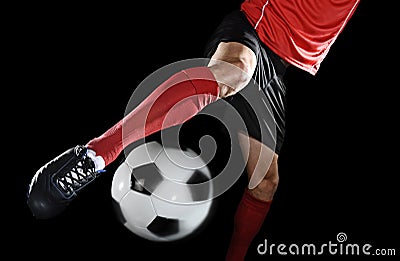 Close up legs and soccer shoe of football player in action kicking ball isolated on black background Stock Photo