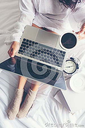 Close up legs women on white bed in the bedroom. Women reading book and drinking coffee in morning relax mood in winter season Stock Photo