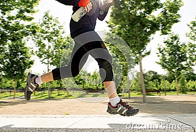 Close up legs of young man running in city park with trees on summer training session practicing sport healthy lifestyle concept Stock Photo