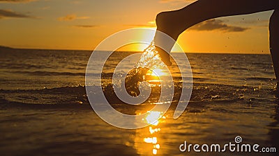CLOSE UP, LENS FLARE: Small water droplets fly off female jogger`s feet running at breathtaking sunset. Stock Photo