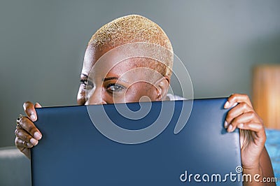 Close up lifestyle portrait of young classy attractive and happy black african american woman posing playful hiding behind laptop Stock Photo