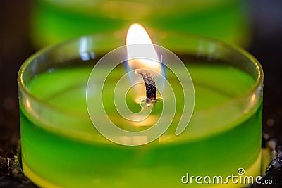 Close up of a lit tea light with green stearine Stock Photo