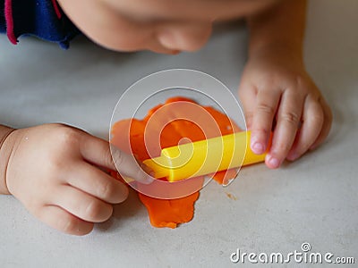 Close up of little baby`s hands rolling on playdough on the house floor Stock Photo