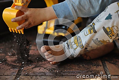 CLOSE UP LITTLE DIRTY BOY PLAYING WITH TOY DIGGER AT HOME WITH Stock Photo