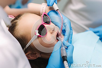 Close up of Little girl in 3D glasses sitting on destal chair at the office and have yearly checkup. Dentist with Stock Photo