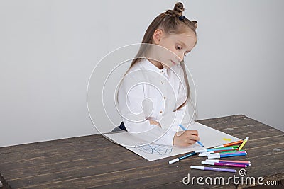 Close up of little girl in white blouse which is focused on drawing. Preschooler is learning how to draw. Kindergarten and school. Stock Photo