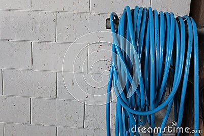 Close-up, lots of plastic blue hose reel, white cement wall background, indoor factory building. Stock Photo
