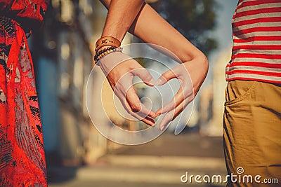 Close up of loving couple making heart shape with hands at city street. Summertime Stock Photo