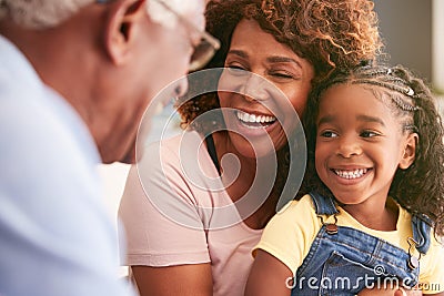 Close up Of Loving Grandparents Cuddling Granddaughter At Home Stock Photo