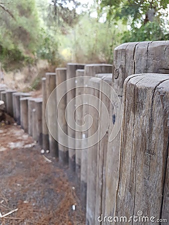A low fence made of wooden trunks in the park Stock Photo