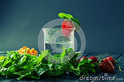 Close up, macro. Refreshing coolness of a lemonade. A glass of water, mint, strawberry. Blue background Stock Photo