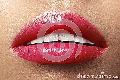 Close-up macro shot of female mouth. Glamour red lips Makeup with sensuality gesture. Magenta gloss lipstick Stock Photo