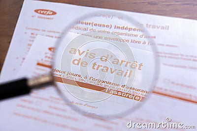 Close-up through a magnifiying glass of an official sick leave form from the French social security Editorial Stock Photo