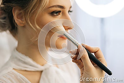 Close-up of make-up artist putting rouge on cheek of young woman using brush Stock Photo