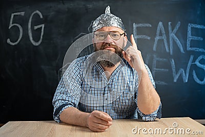 close-up of a male conspiracy theorist in a protective foil cap and glasses debunks myths. Conspiracy theory and the Stock Photo