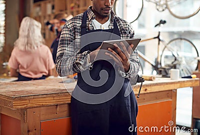 Close Up Of Male Craftsman In Carpentry Workshop For Bamboo Bicycles Using Digital Tablet Stock Photo