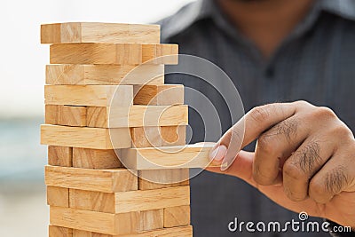 Close up male hand holding arranging or pick up the block wood game and stacking. Growth of Business financial investment and Stock Photo