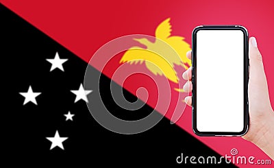 Close-up of male hand holding smartphone with blank on screen, on background of blurred flag of Papua New Guinea Stock Photo