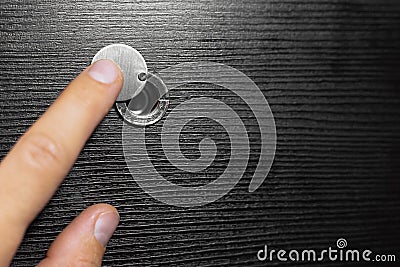 Close-up of male hand opening the peephole of the wooden door. Stock Photo