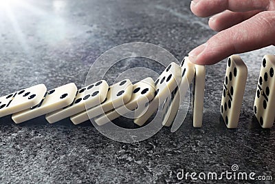 Close-up of male hand preventing line of domino tiles from toppling and falling Stock Photo