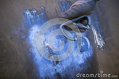 Close up male hand wearing a black glove using industrial lock carabiner clipping into safety lifting lug Stock Photo