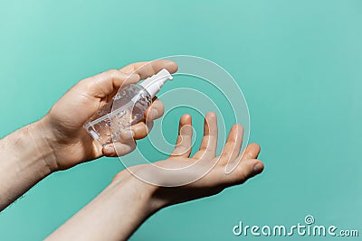 Close-up of male hands applying sanitizer antiseptic gel on background of aqua menthe color. Man using bottle of antibacterial. Stock Photo