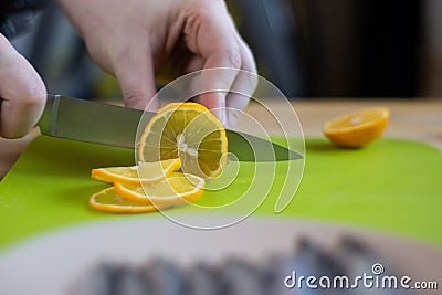 Male hands cut lemon on green cutting board, close up Stock Photo