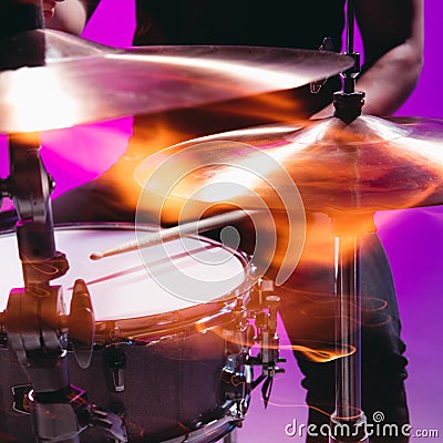 Close-up male hands playing the drums isolated on blue-pink background in neon Stock Photo