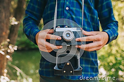 Close up of male photographer hands holding retro camera on green garden background. Stock Photo