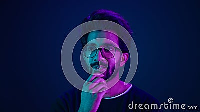 Close up male portrait in neon studio ultraviolet background blue backdrop Arabian Muslim shocked amazed guy astonish Stock Photo