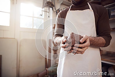 Close Up Of Male Potter Wearing Apron Holding Lump Of Clay In Ceramics Studio Stock Photo