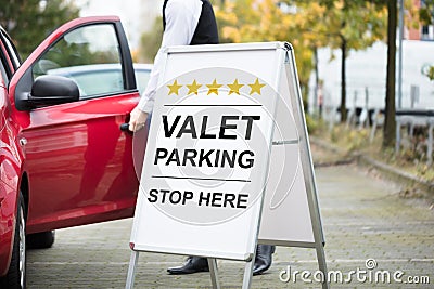 Young Male Valet Standing Near Valet Parking Sign Stock Photo