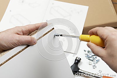 Close Up Of Man Assembling Flat Pack Furniture With Screwdriver Stock Photo