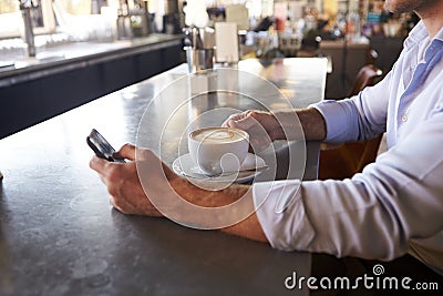 Close Up Of Man Checking Messages On Phone In Coffee Shop Stock Photo