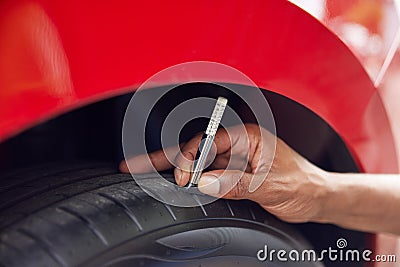 Close-Up Of Man Checking Tread On Car Tyre With Gauge Stock Photo