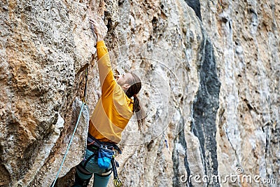 close up man climber climbing on high rock gliff, making hard move up, gripping hold Stock Photo