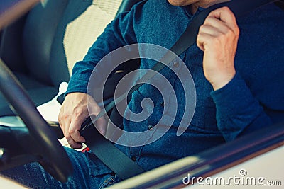 Close up man driver fastening seat belt. Guy seated behind the steering wheel testing his new car safety Stock Photo