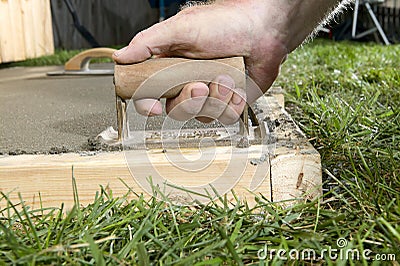 Close up of man finishing cement slab with edger Stock Photo