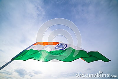 Close up man hand holding India flag on the blue sky background. Stock Photo