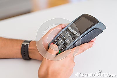Close up of man hands holding point of sale terminal, dataphone for shopping paying using credit card Stock Photo